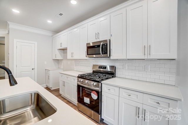 kitchen featuring sink, crown molding, white cabinets, and appliances with stainless steel finishes