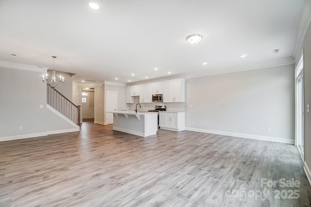 unfurnished living room with a notable chandelier, ornamental molding, light hardwood / wood-style floors, and sink