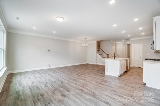 kitchen with white cabinets, stainless steel appliances, a center island with sink, and light hardwood / wood-style floors