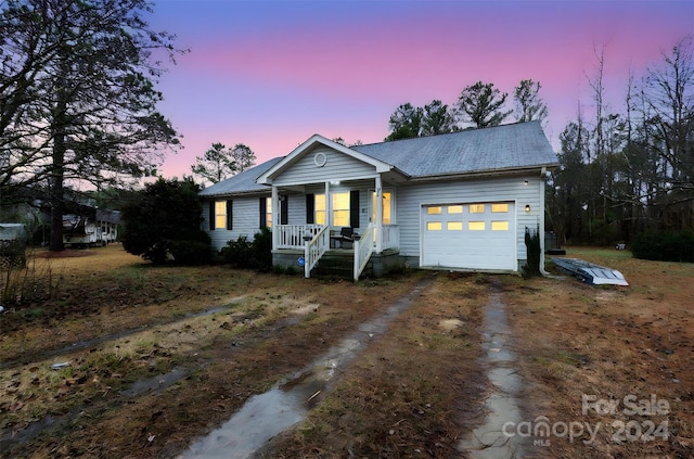 single story home featuring a porch and a garage