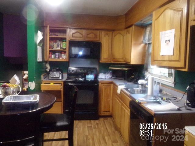 kitchen with sink, black appliances, and light wood-type flooring