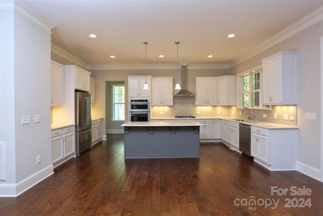 kitchen featuring wall chimney exhaust hood, dark wood-type flooring, stainless steel appliances, pendant lighting, and a kitchen island