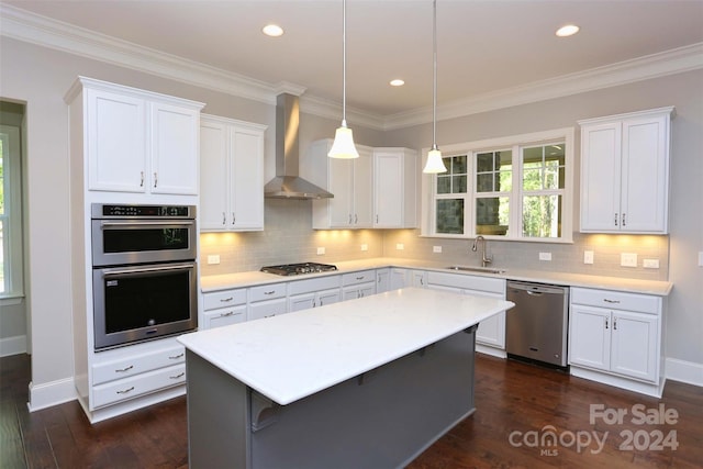 kitchen featuring a center island, sink, wall chimney exhaust hood, appliances with stainless steel finishes, and white cabinetry