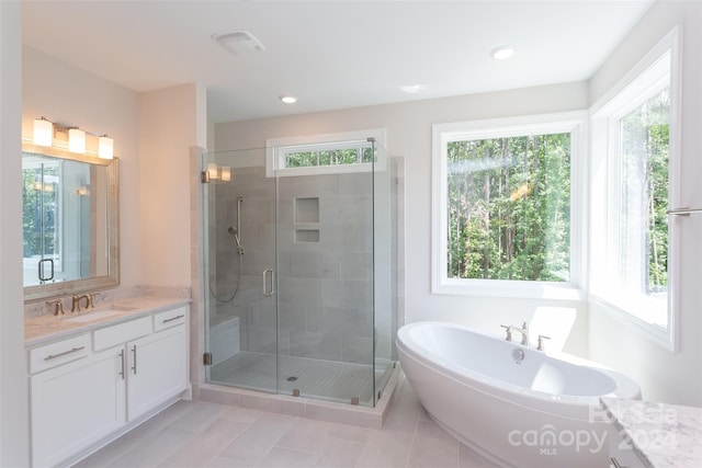 bathroom with tile patterned flooring, vanity, separate shower and tub, and a wealth of natural light