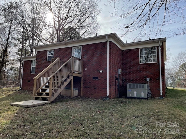 back of property featuring central AC unit and a lawn