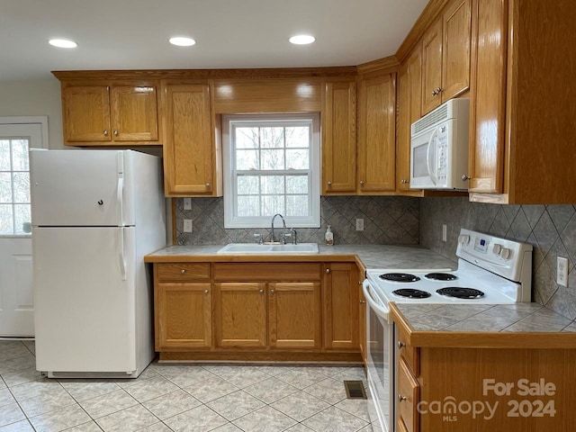 kitchen with tile countertops, white appliances, sink, and a wealth of natural light