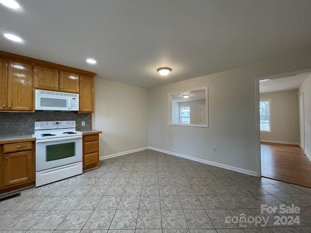 kitchen with light tile patterned floors, a healthy amount of sunlight, and white appliances