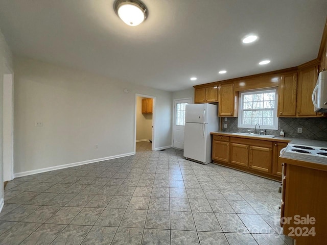 kitchen featuring backsplash, sink, light tile patterned floors, and white appliances