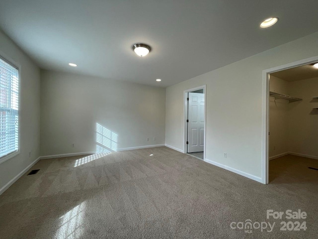 unfurnished bedroom featuring carpet flooring, a spacious closet, and a closet