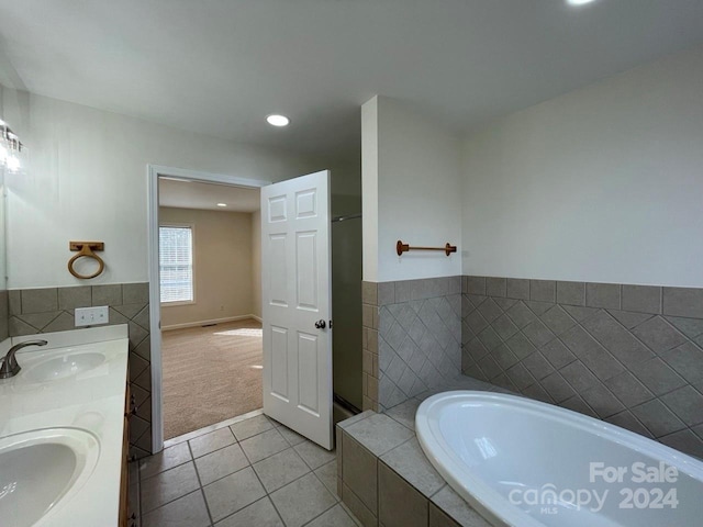 bathroom with tile patterned floors, vanity, and a relaxing tiled tub