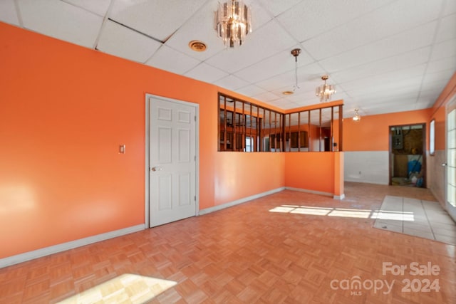 empty room with a drop ceiling and parquet floors