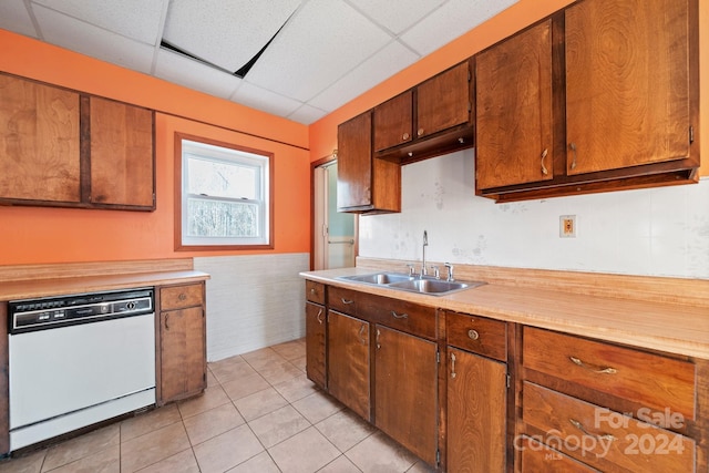 kitchen featuring white dishwasher, a drop ceiling, light tile patterned flooring, and sink