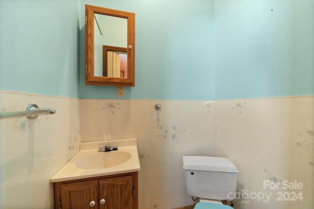 bathroom featuring vanity, toilet, and tile walls