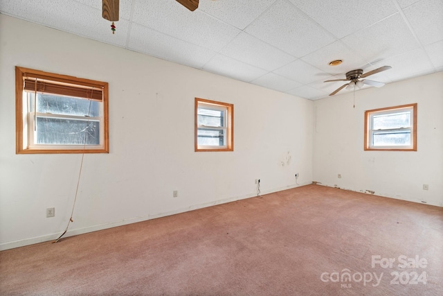 empty room with carpet flooring, a paneled ceiling, plenty of natural light, and ceiling fan