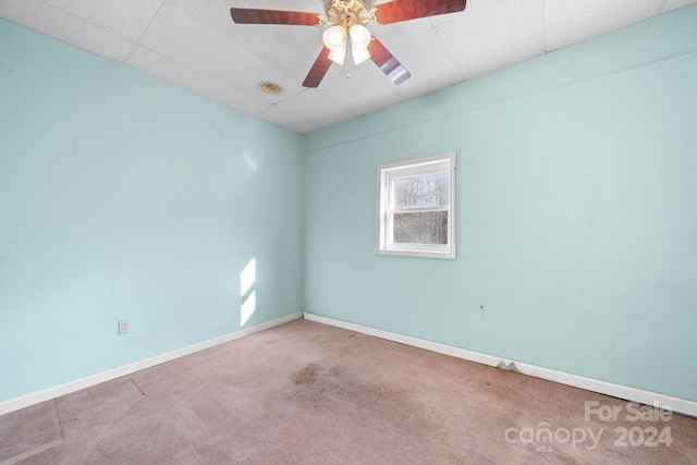 carpeted empty room with a paneled ceiling and ceiling fan