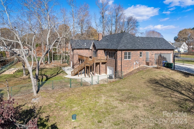 rear view of house with a lawn, a wooden deck, and a garage