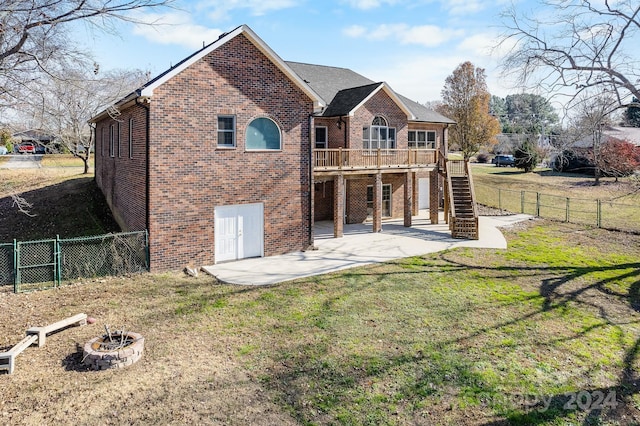 back of property featuring a yard, a deck, a patio, and an outdoor fire pit