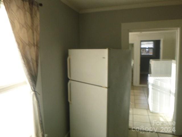 kitchen with light tile patterned floors, white refrigerator, and crown molding