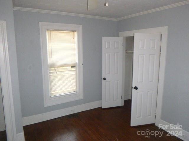 unfurnished bedroom with crown molding and dark hardwood / wood-style floors