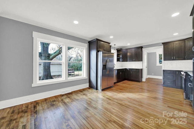 kitchen with light hardwood / wood-style flooring, backsplash, dark brown cabinets, and stainless steel appliances