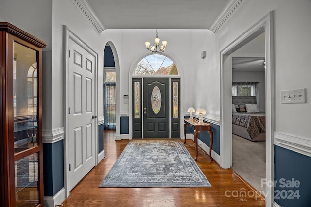 foyer entrance with hardwood / wood-style floors, ornamental molding, and an inviting chandelier