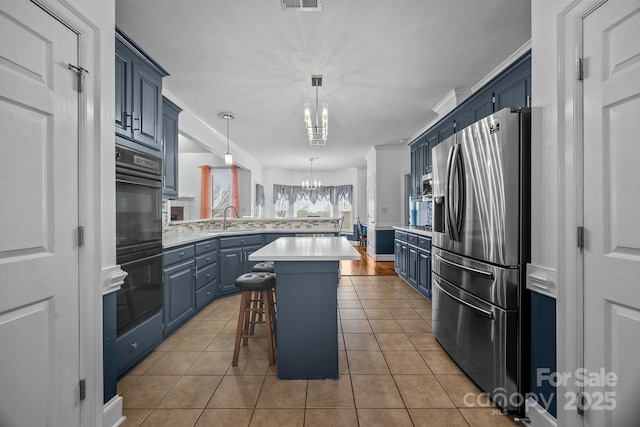 kitchen with a center island, stainless steel fridge, a kitchen breakfast bar, a notable chandelier, and pendant lighting