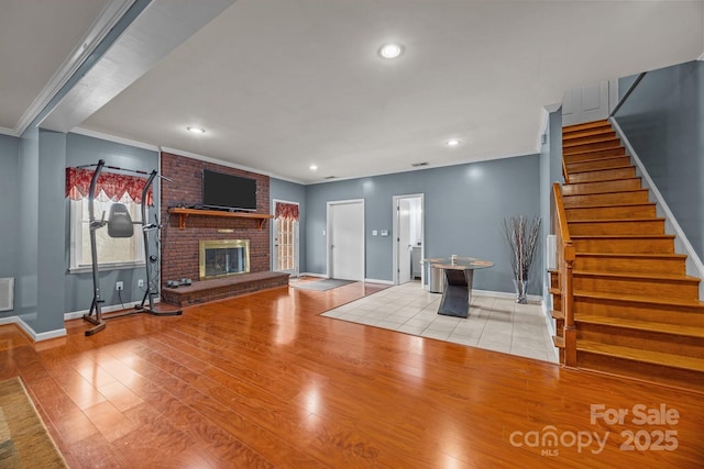 unfurnished living room featuring crown molding, a brick fireplace, and light hardwood / wood-style floors