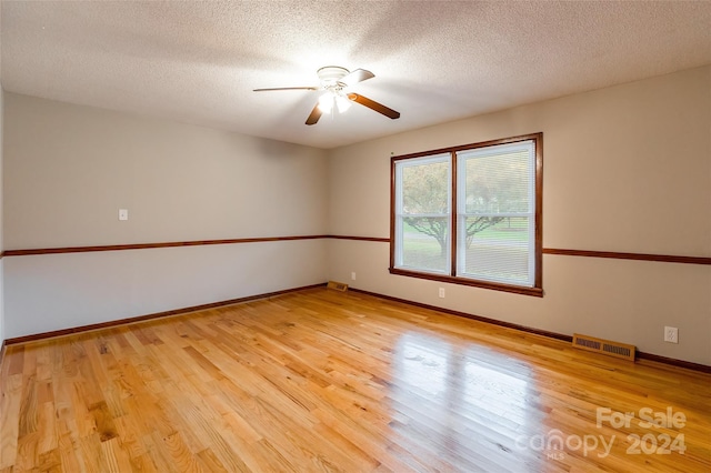 empty room with ceiling fan, light hardwood / wood-style floors, and a textured ceiling