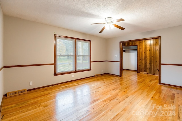 unfurnished bedroom featuring ceiling fan, a closet, a textured ceiling, and light wood-type flooring