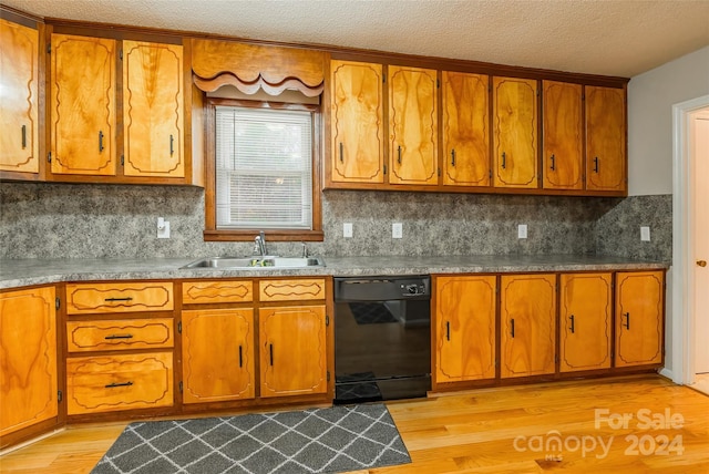 kitchen featuring backsplash, sink, light wood-type flooring, and black dishwasher