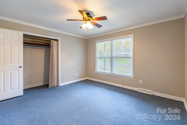 unfurnished bedroom with ceiling fan, a closet, dark carpet, and ornamental molding