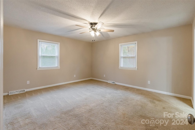 carpeted spare room with ceiling fan and a textured ceiling