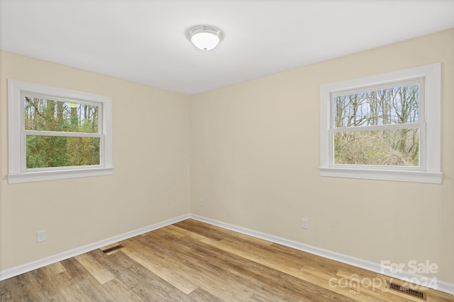 empty room with a healthy amount of sunlight and wood-type flooring