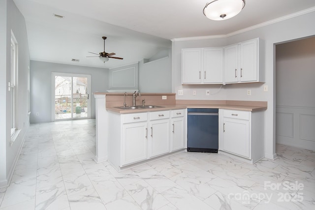 kitchen with ceiling fan, sink, kitchen peninsula, white cabinets, and ornamental molding