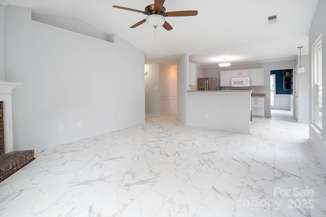 unfurnished living room with ceiling fan, vaulted ceiling, and a brick fireplace