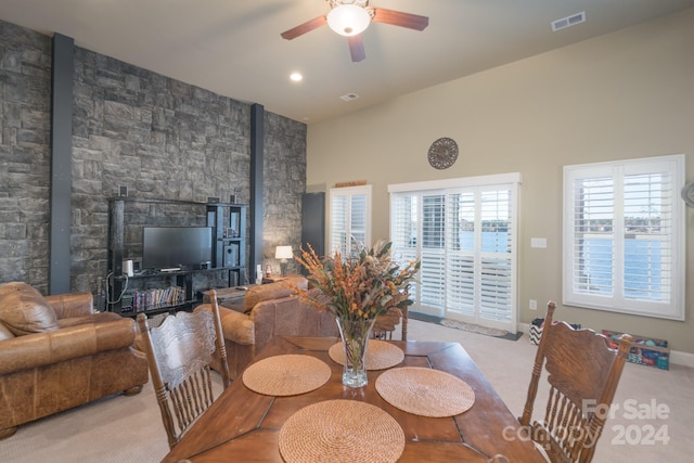 dining area featuring ceiling fan, light colored carpet, and high vaulted ceiling