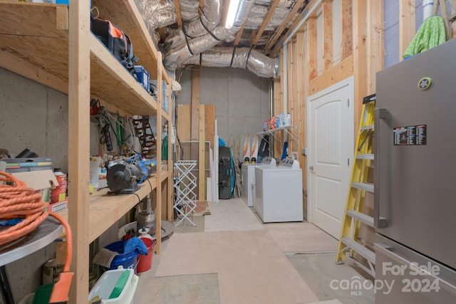 basement with stainless steel fridge, a workshop area, and washing machine and dryer