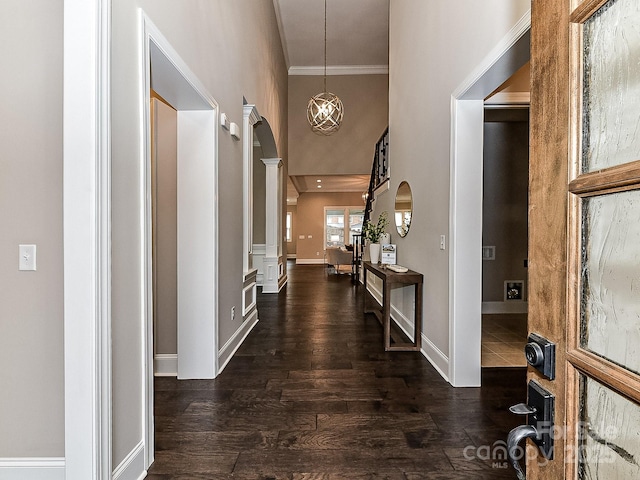 entryway with ornamental molding, dark wood-type flooring, and a high ceiling