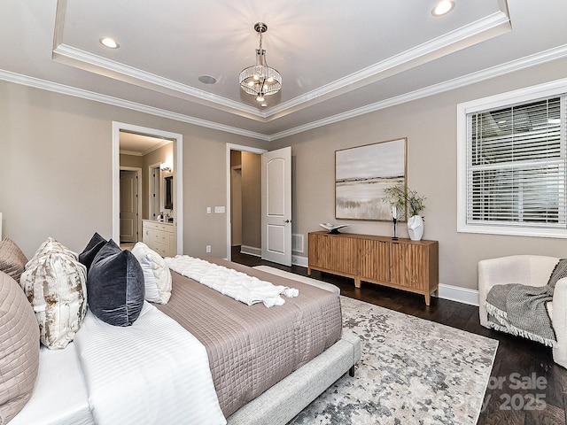 bedroom with a chandelier, crown molding, dark wood-type flooring, connected bathroom, and a raised ceiling