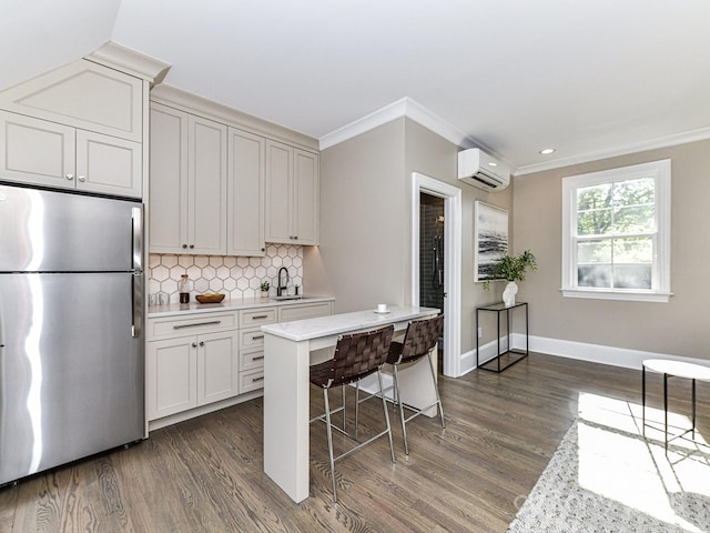 kitchen featuring a breakfast bar, stainless steel refrigerator, sink, crown molding, and decorative backsplash