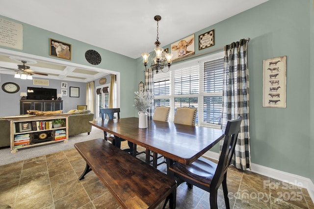 dining space with baseboards, stone finish floor, ceiling fan with notable chandelier, and coffered ceiling