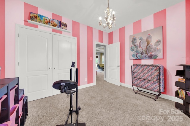 exercise area featuring an inviting chandelier, carpet floors, and baseboards