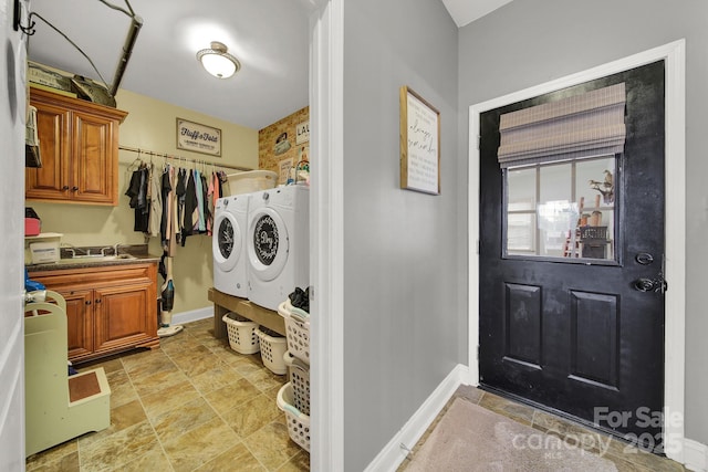 laundry area featuring baseboards, washer and clothes dryer, stone finish flooring, and cabinet space