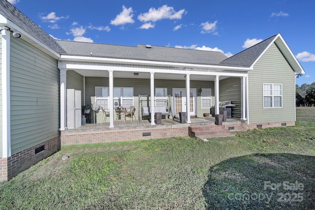 back of property with a lawn, a shingled roof, and crawl space