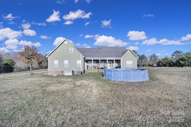 back of property featuring central AC unit, a yard, and an outdoor pool