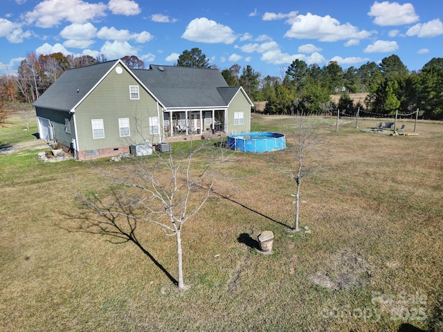 rear view of property featuring a shingled roof, an outdoor pool, a yard, and crawl space