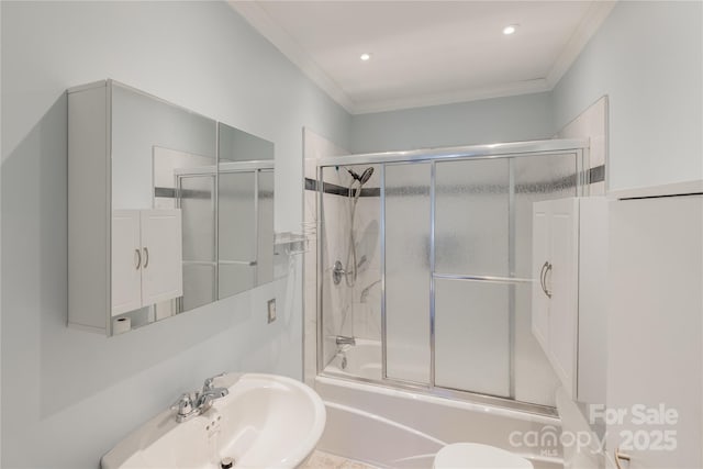 bathroom with combined bath / shower with glass door, crown molding, and sink