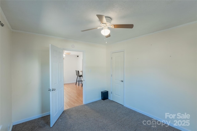 unfurnished bedroom featuring ceiling fan, carpet floors, and crown molding