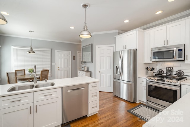 kitchen featuring appliances with stainless steel finishes, sink, pendant lighting, hardwood / wood-style flooring, and white cabinets