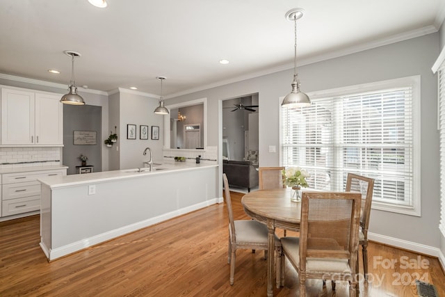 dining room with light hardwood / wood-style flooring, ceiling fan, ornamental molding, and sink